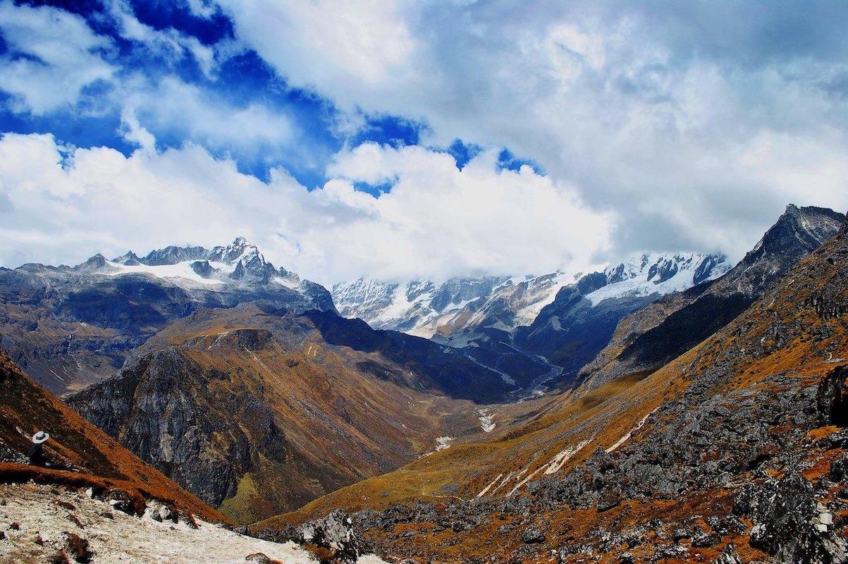 Blue sky fill with cloud and a river flowing from the distant snow covered mountains to the valley