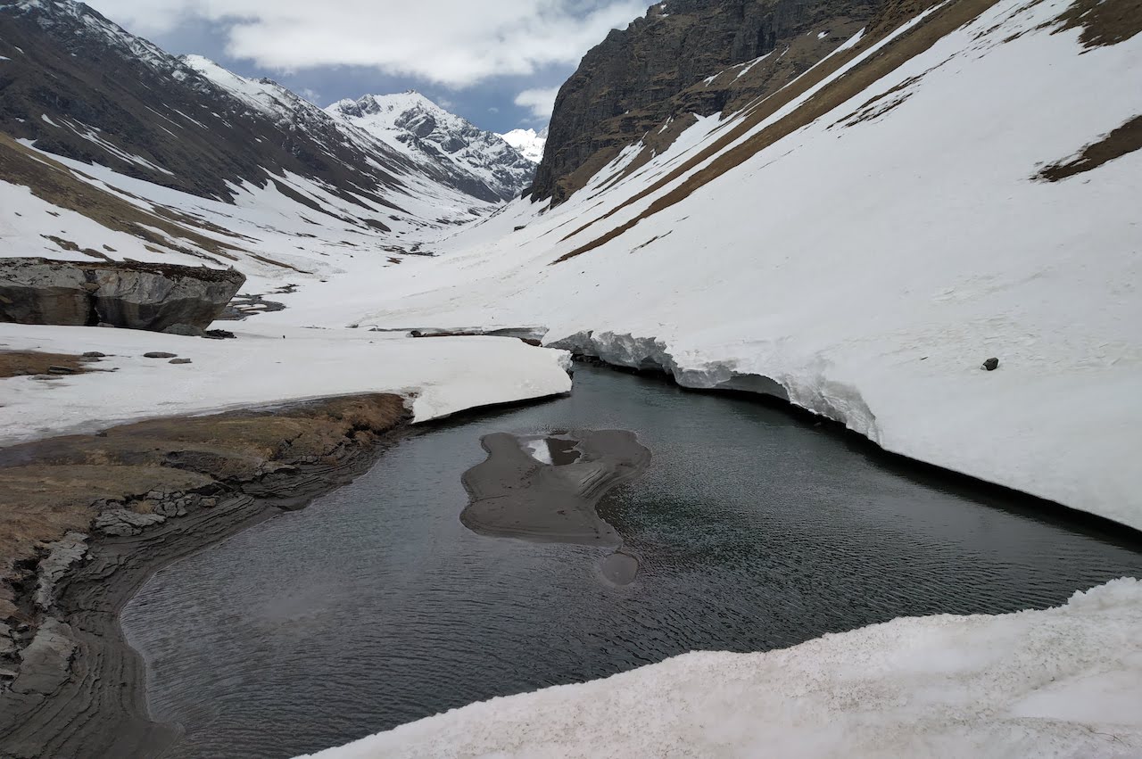 Maninda lake in the valley covered with snow and beautiful mountains with blue sky with clouds above