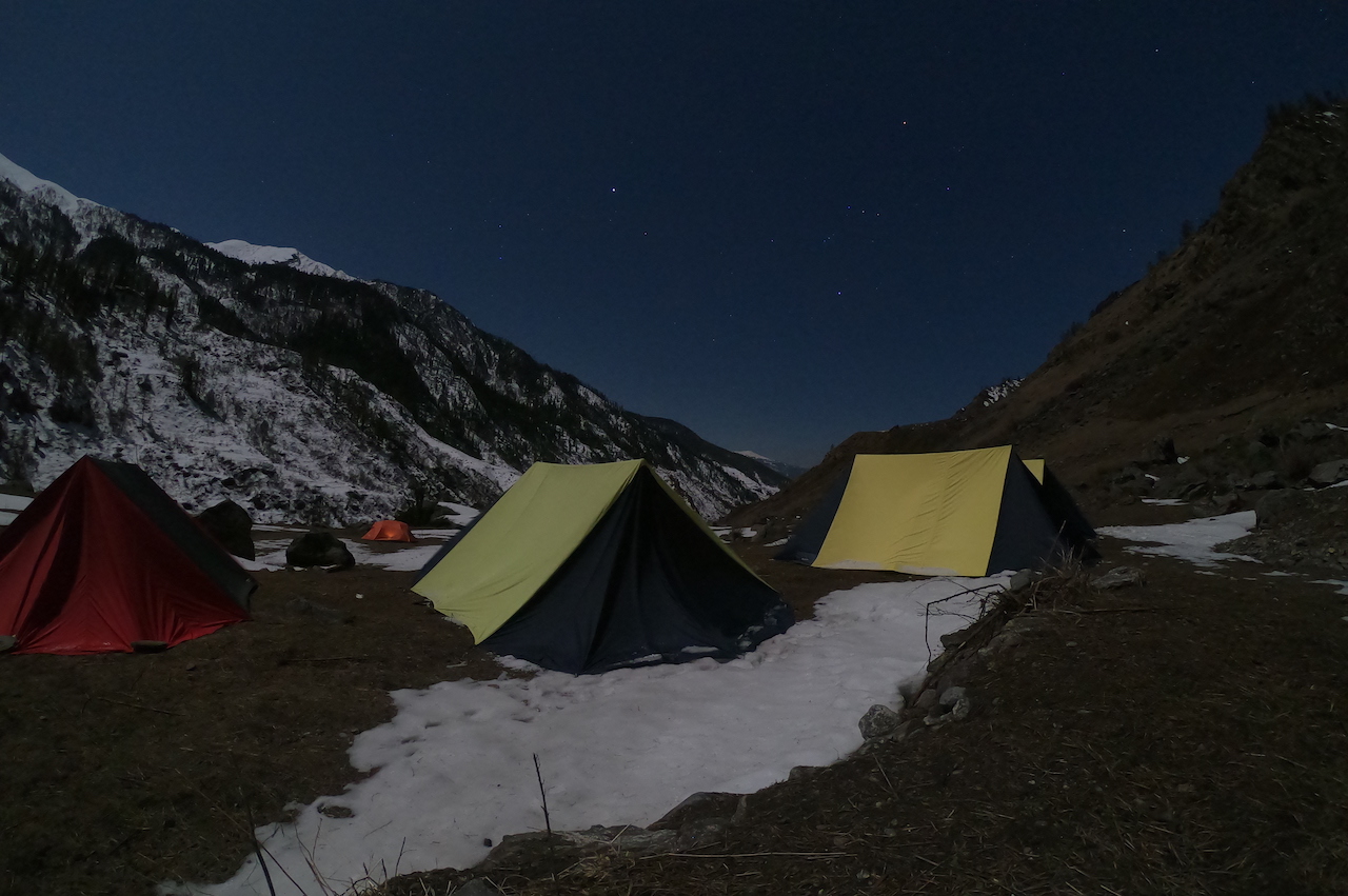 Campsite at the foot of snow covered mountain under the sky full of stars