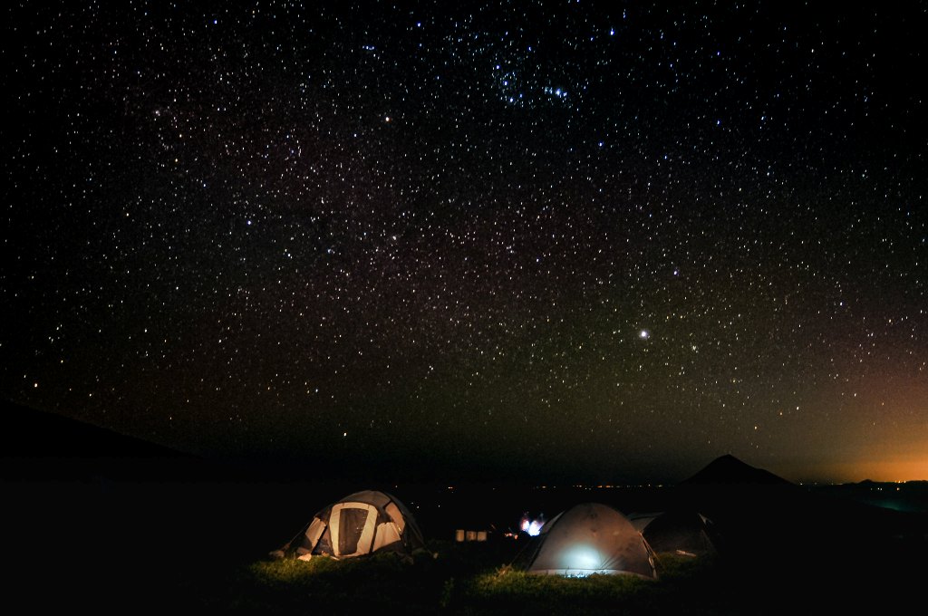 couple of tent pitched on ground at the night with sky full of stars