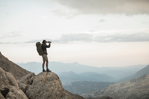 Trekker having water while standing on a rock