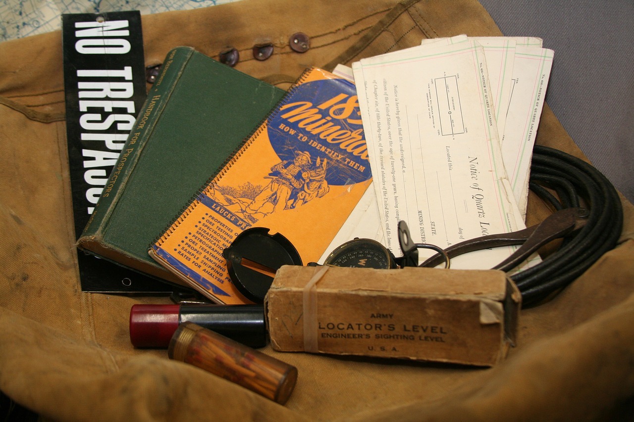 A ice axe, rope, couple of books, a compass placed over a brown bag