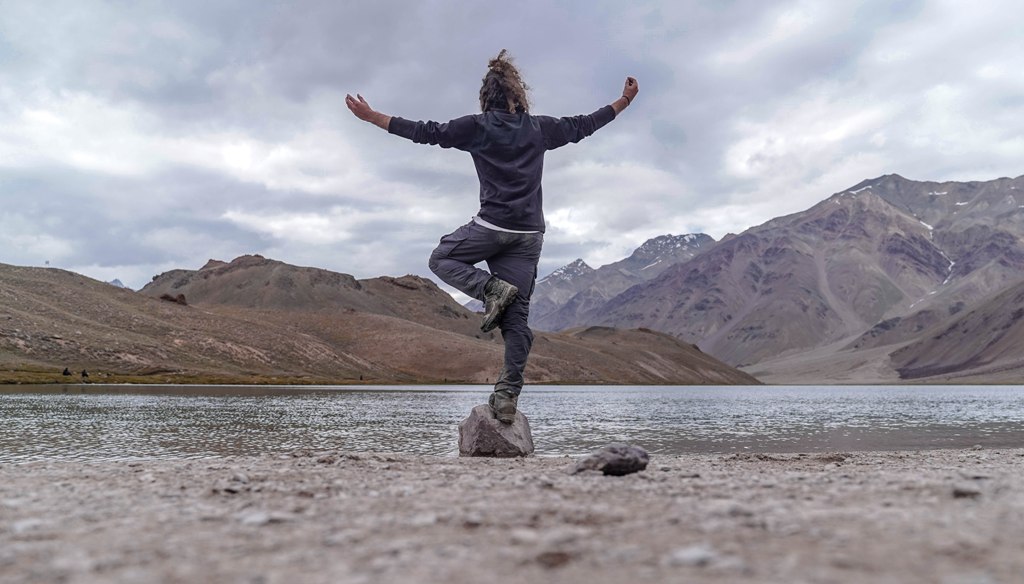 man standing at rock doing yoga