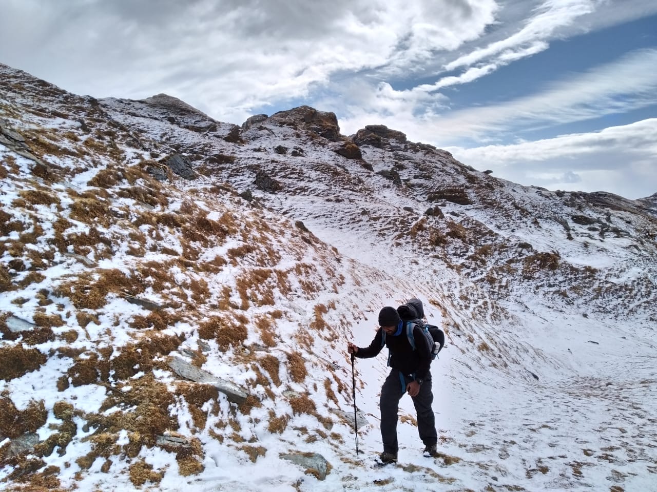 trekker holding trekking stick walking over snow covered ground