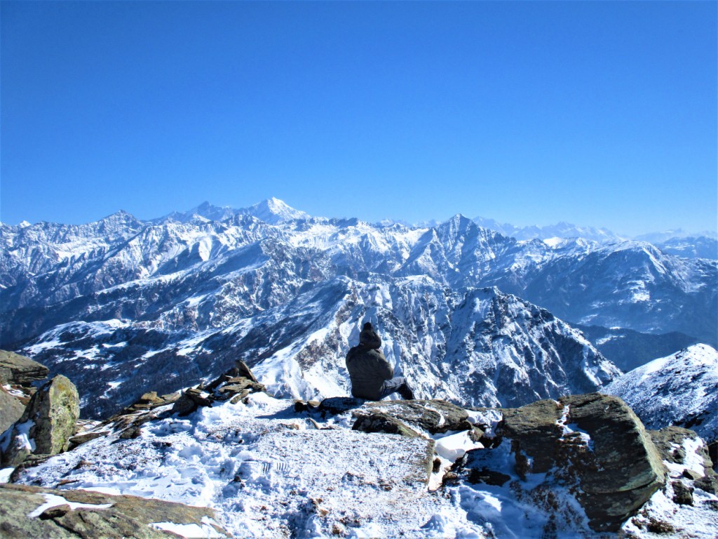 Trekker sitting at the edge at kedarkantha summit