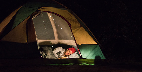 reading at night in a tent while camping