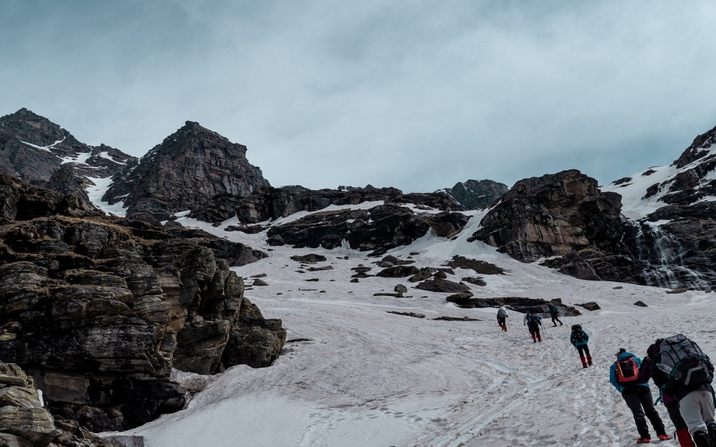 trekkers heading toward the snow capped rupin pass