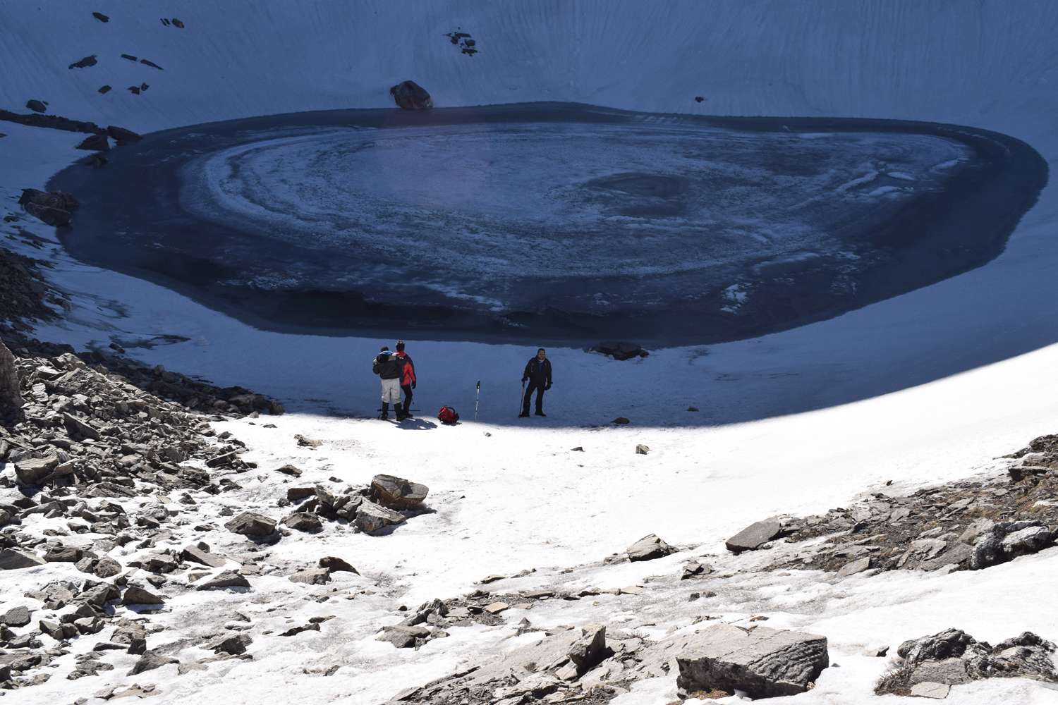 3 people standing over frozen roopkund lake